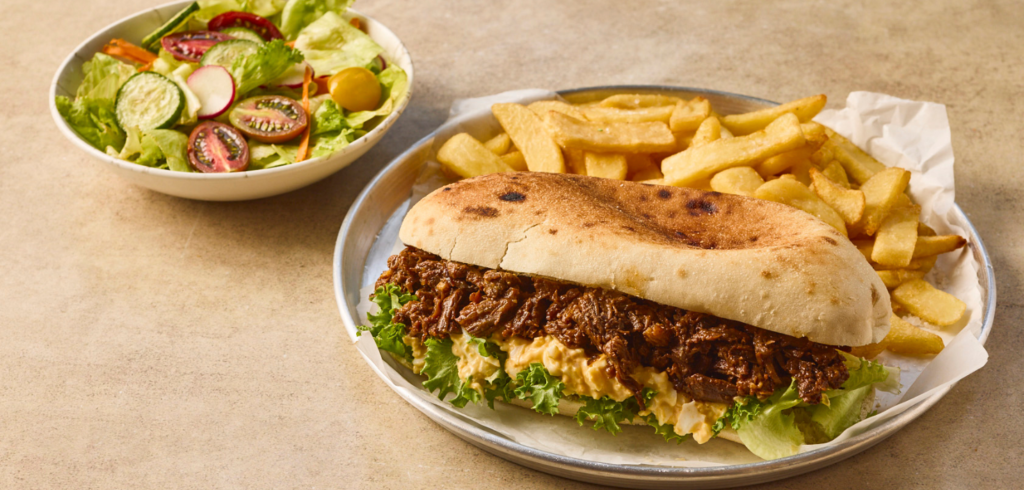 כריך עסיסי של בשר מפורק עם סלט ביצים בג׳בטה טריה עם צ׳יפס זהוב וסלט טרי בצד